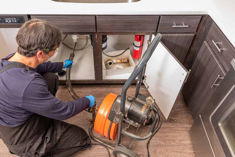 plumber unclogging a pantry sink drain